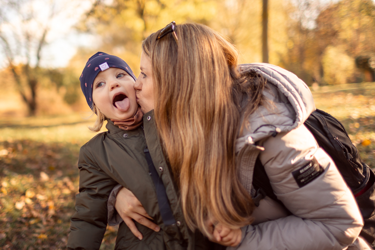 Mutter küsst ihren Sohn im Herbstlaub
