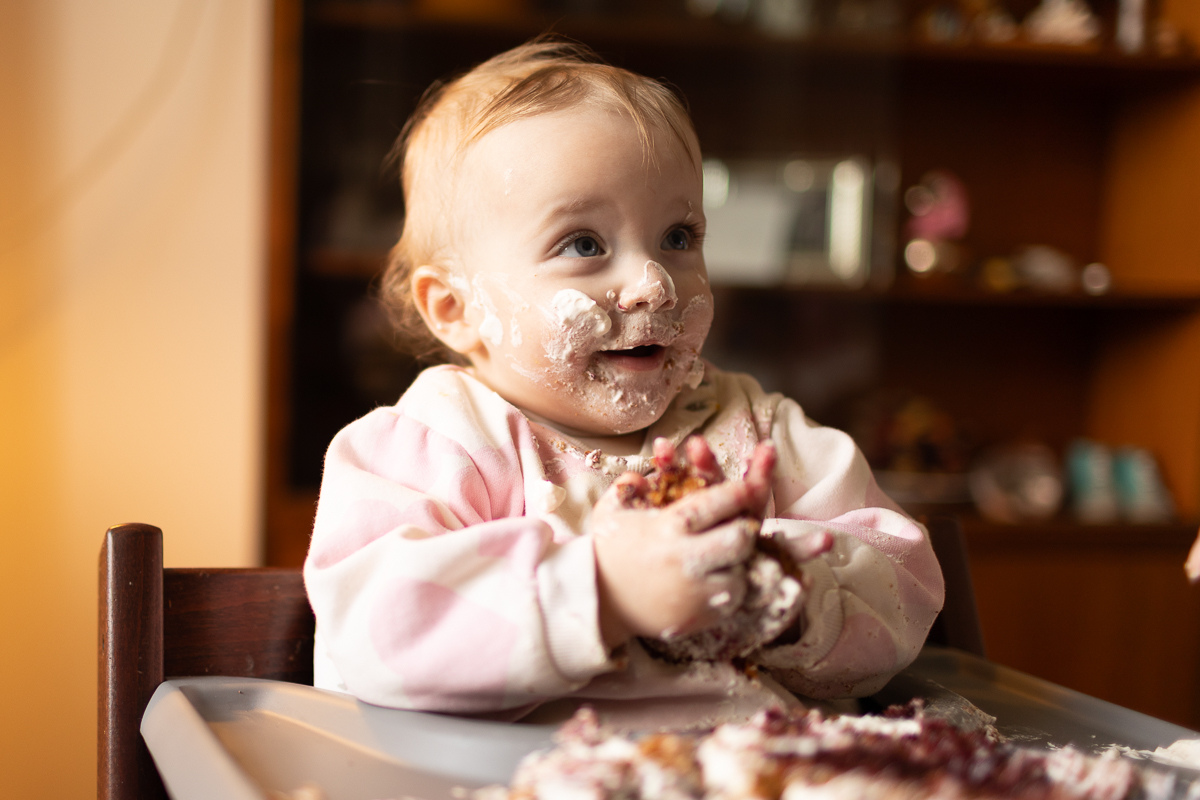 Baby mit Kuchen im Gesicht beim ersten Geburtstag