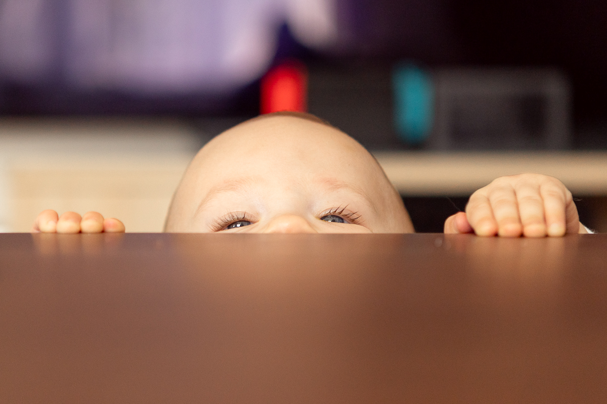 Baby schaut neugierig über die Tischkante