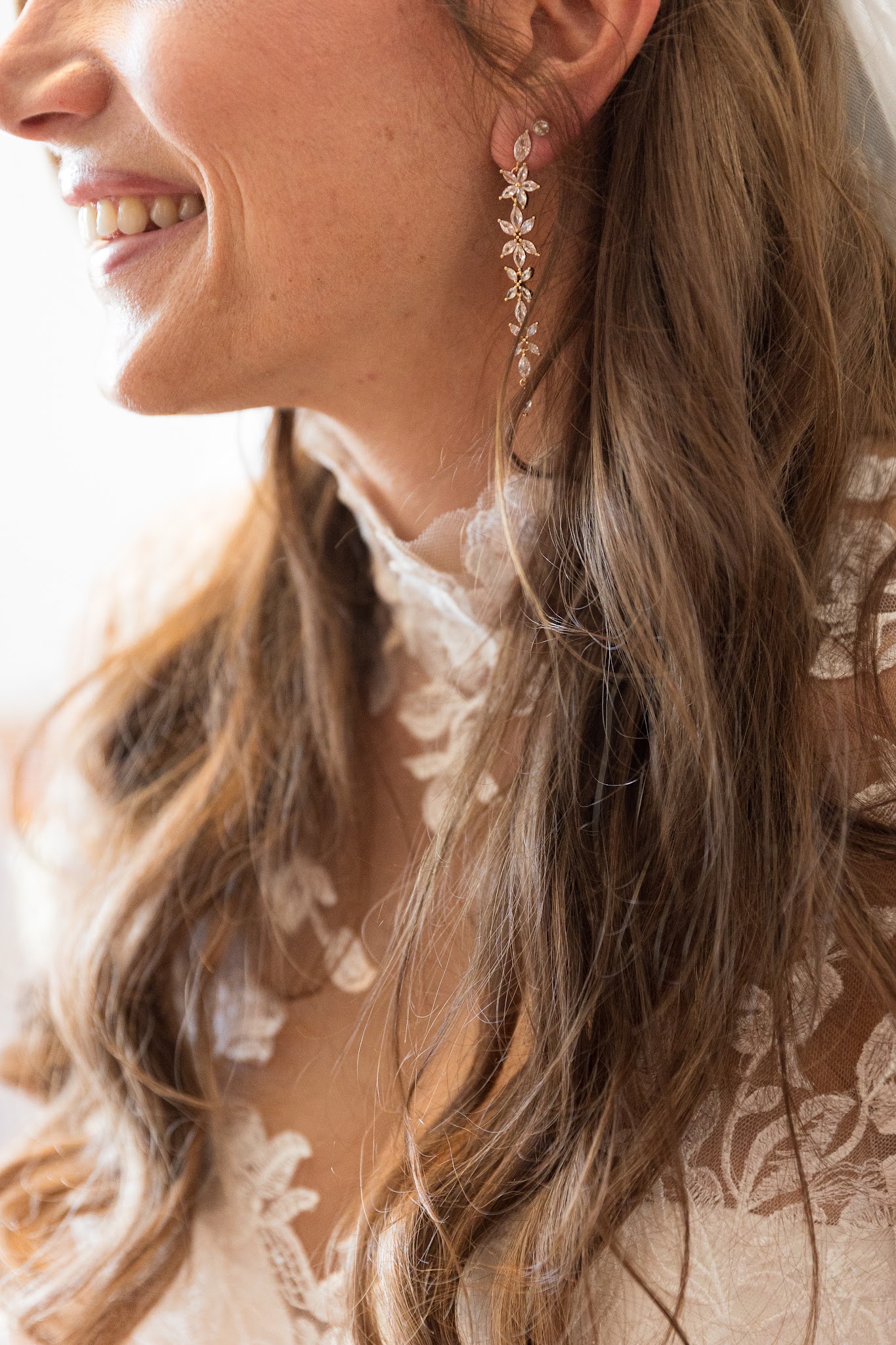 Braut lacht, Detail mit Ohrring und Spitze