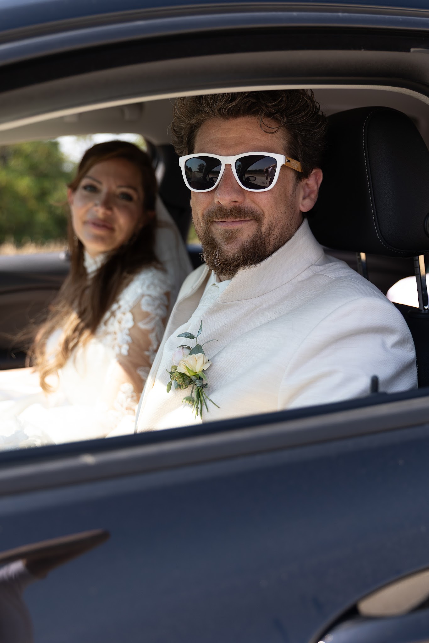 Brautpaar mit Sonnenbrillen im Auto